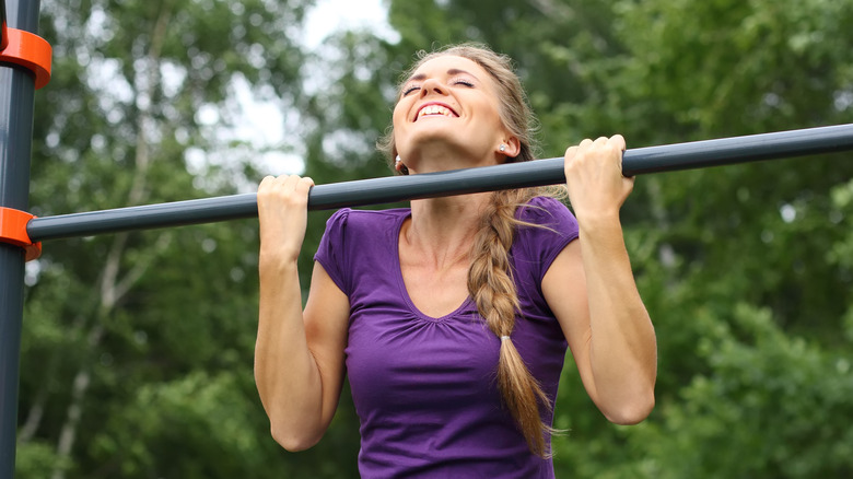 smiling woman doing chin-ups 