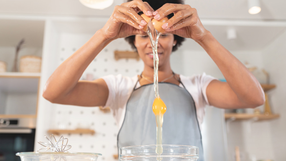 Woman cracking an egg that is falling into a bowl 
