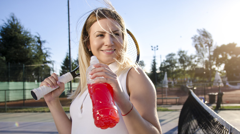 Female tennis player holding an electrolyte beverage 
