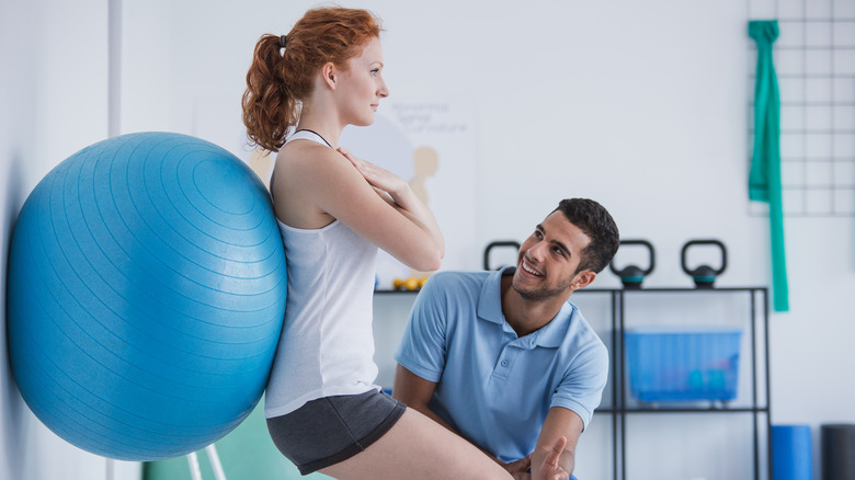 Young woman doing postural exercises with an exercise ball