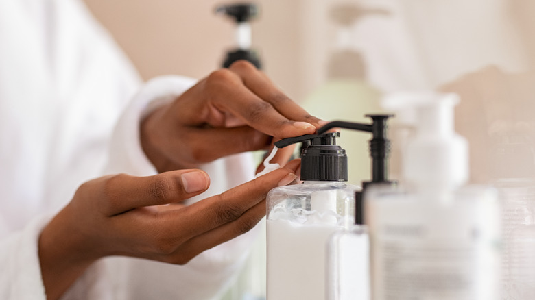 Hands pressing lotion dispenser