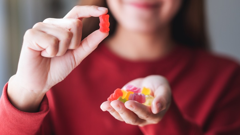 Woman holding different colors of gummy bears