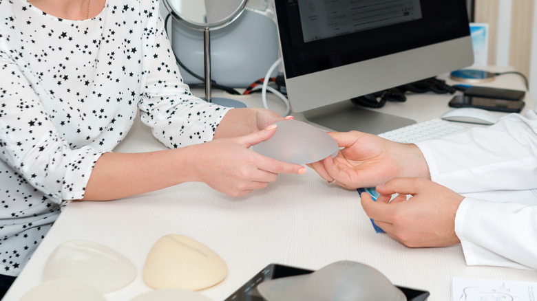 Doctor handing patient silicone breast implant
