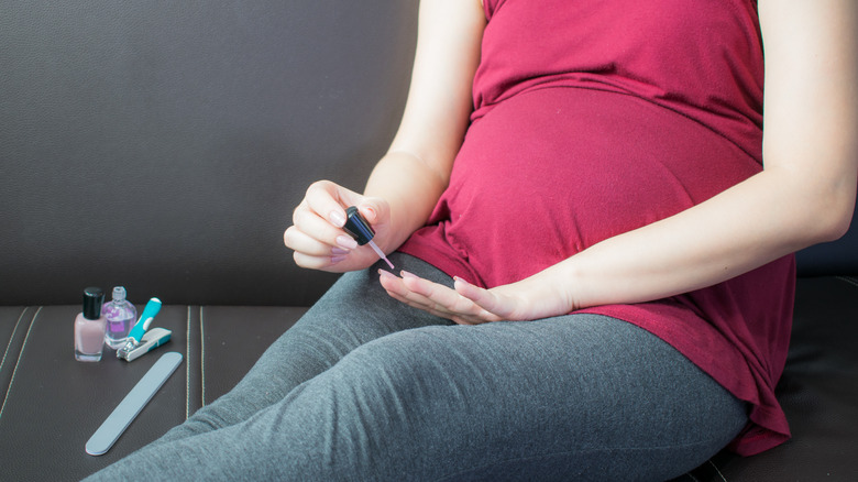 pregnant woman paints her nails 