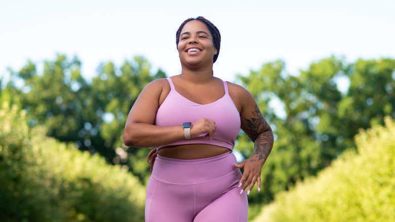 A smiling woman running outdoors.