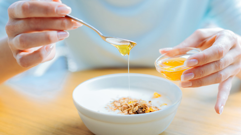 woman adding honey to her yogurt