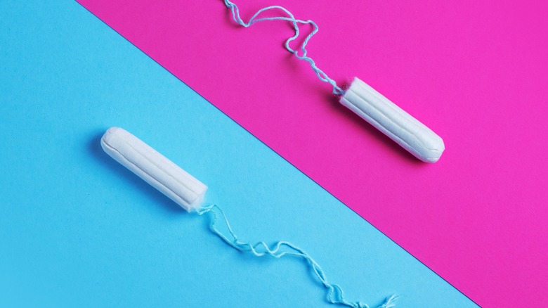 Two tampons without applicators over a background split into blue and pink