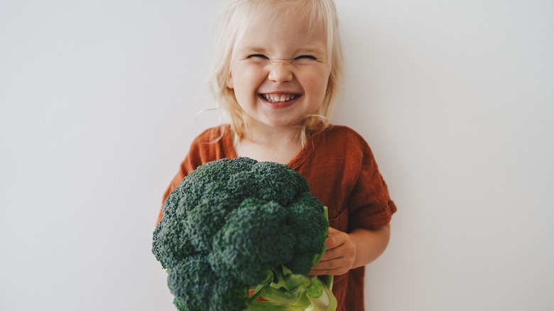 Little girl holding broccoli