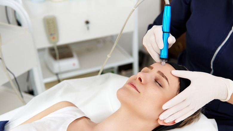 A doctor uses a pore vacuum on a woman's face