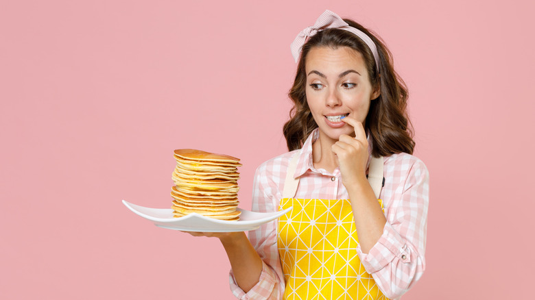 woman holds plate of pancakes