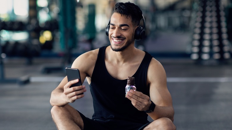 man sitting in gym eating snack bar