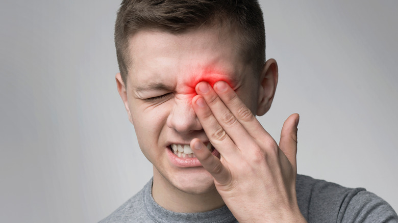 Man holding his hand over his eye