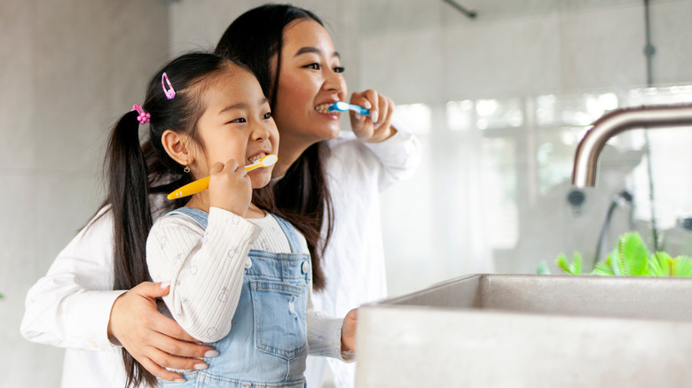 woman and young girl brushing teeth