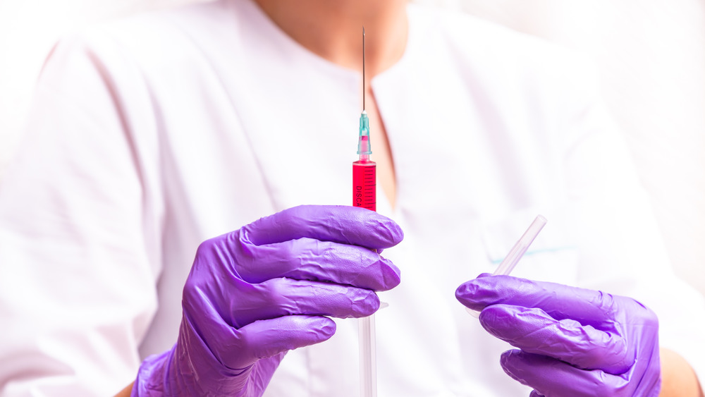 Woman holding syringe and ampule with B12. 