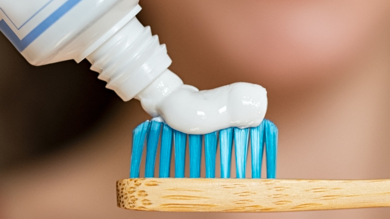 white woman applying toothpaste on toothrbush