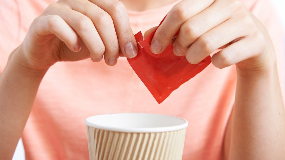 Woman Adding Artificial Sweetener To Coffee