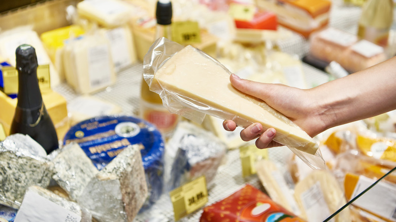 Hand holding block of cheese at grocery store