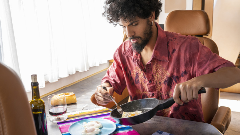 man sliding a fried egg onto his plate