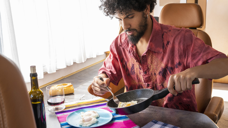 man sliding a fried egg onto his plate