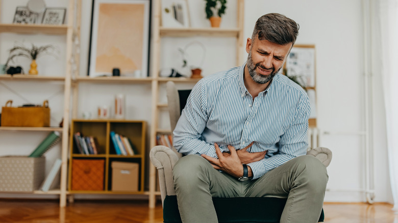 man holding abdomen and looking pained