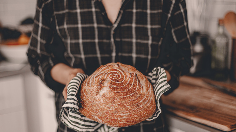 Hands holding boule of sourdough bread