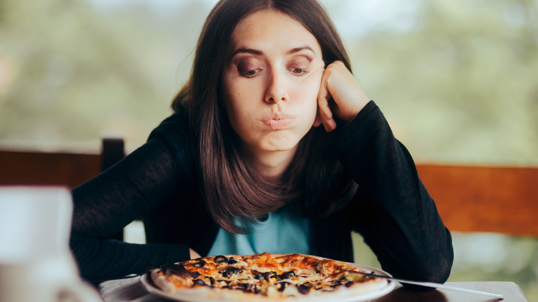 Woman contemplating to eat pizza on her plate