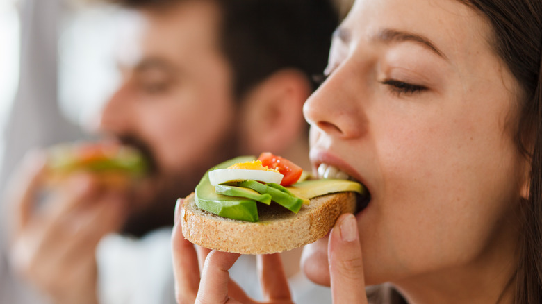 man and woman eating avocado toast