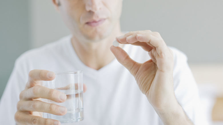 man looking at his pill before taking it