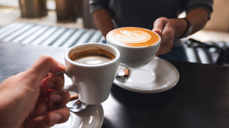 two people doing "cheers" with coffee 