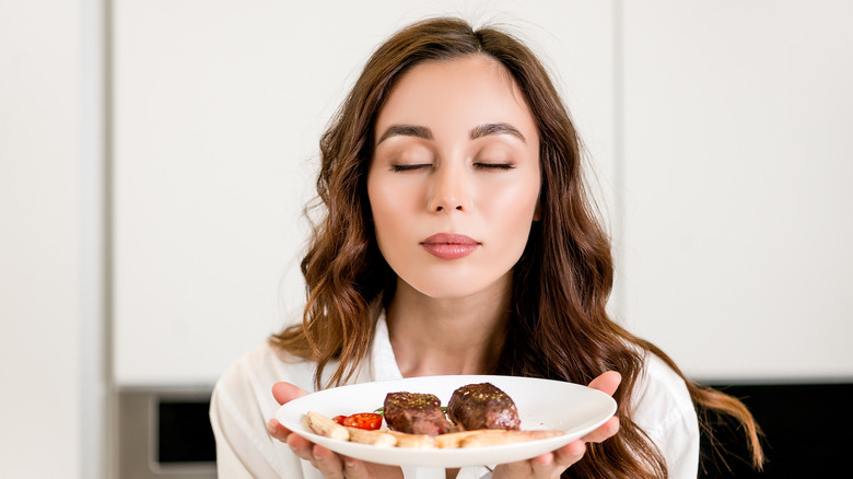 Woman holding a plate with steak and vegetables