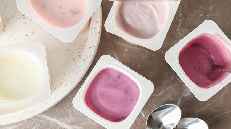 Composition with plastic cups with yogurt on grey table