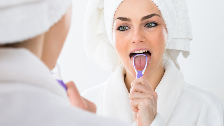 Woman scraping her tongue
