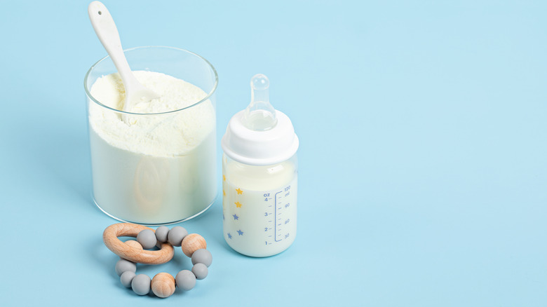 dry baby formula in cup next to bottle of formula