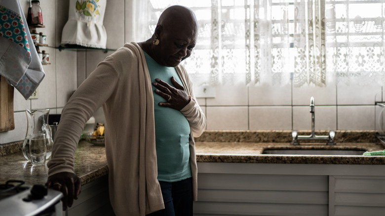 Wincing woman holding chest in pain