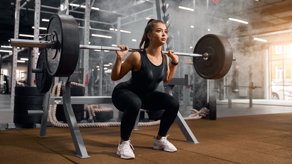 A woman performs a back squat in the gym