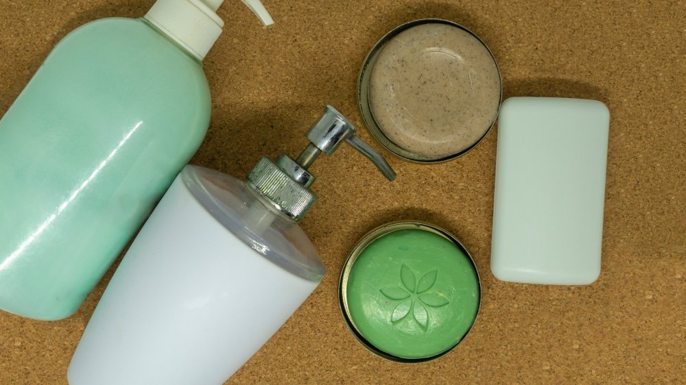 Flat lay composition of liquid and hard soaps on neutral background - an option for Eco switch. Useful for articles for zero-waste, Eco-friendly and green minded focus. Plastic bottles vs metal boxes.