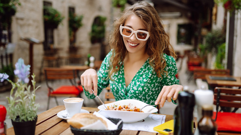A woman enjoying a pasta dish at an outdoor cafe