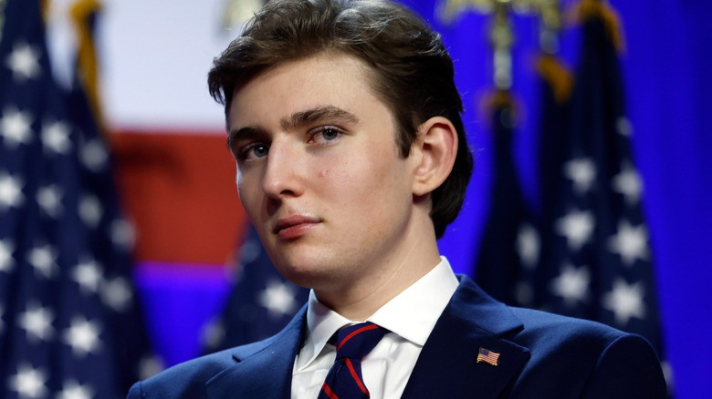 barron trump in formal suit with flags in the background