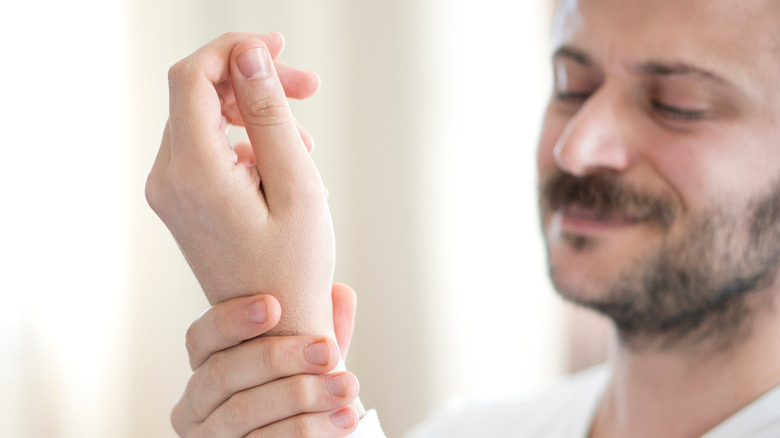 Smiling man rubbing wrist