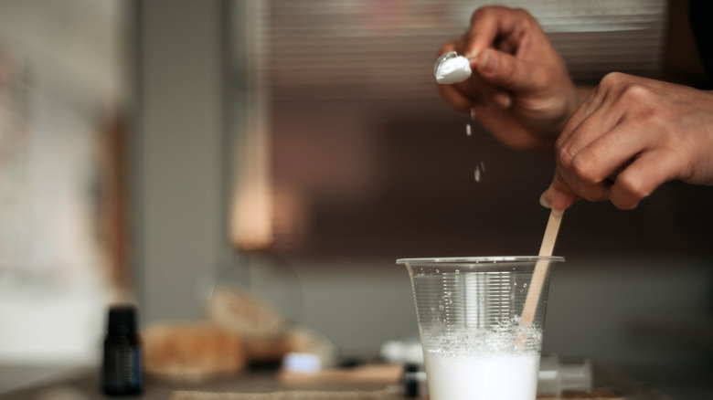 woman's hand pouring baking soda into glass of water