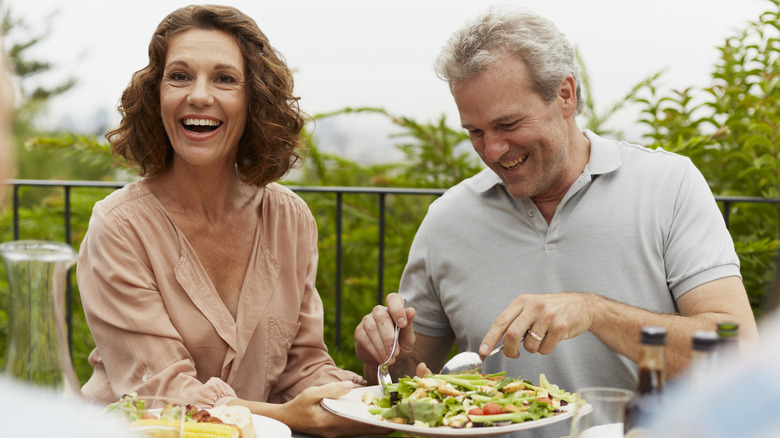 Two older adults eating a salad