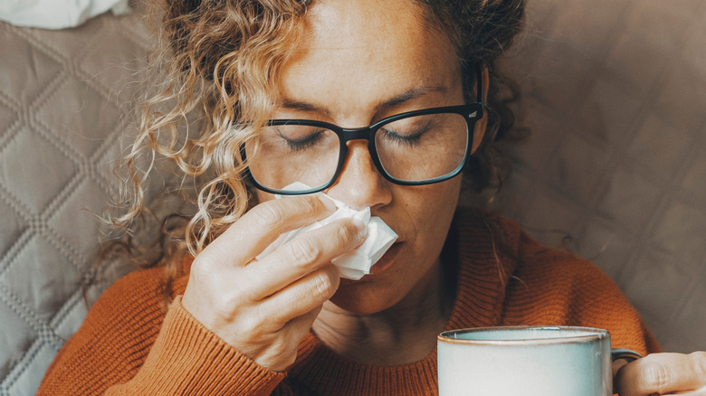 Woman holding mug and tissue