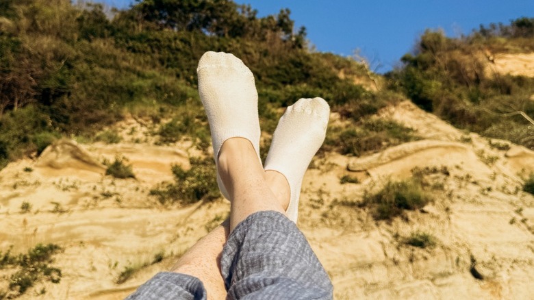 A person wearing white socks while resting on a sandy beach
