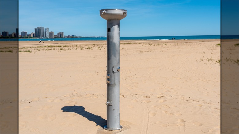 A metal outdoor public shower on a sandy beach
