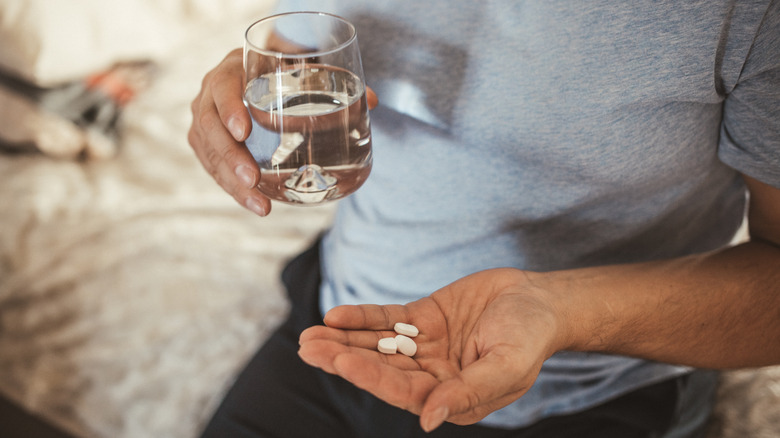Man with water glass about to take pill
