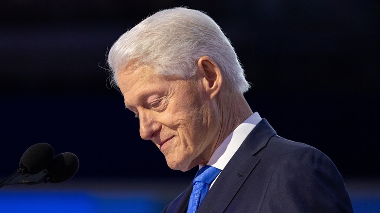 Bill Clinton with head down at a public event