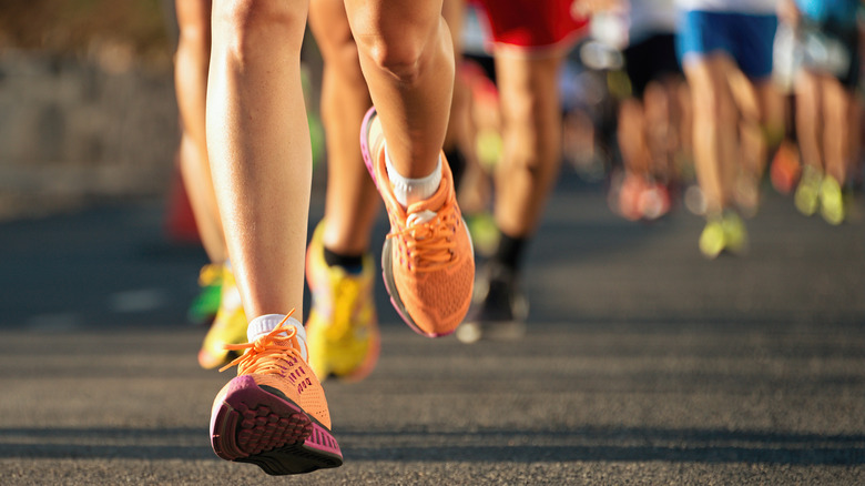 A series of runners, running on a black street, focused on their shoes.