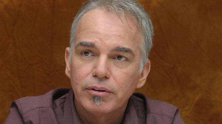 Billy Bob Thornton in front of a brown background, looking off to the left.