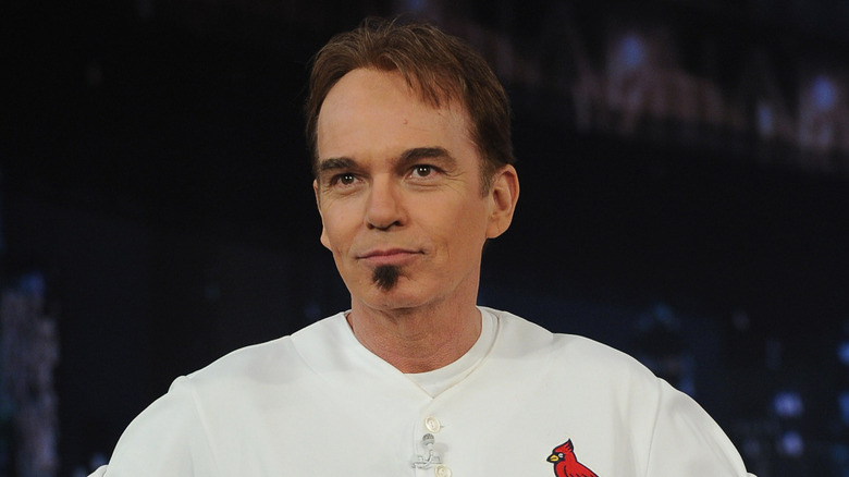 Billy Bob Thorton in a white shirt in front of a black and blue background.