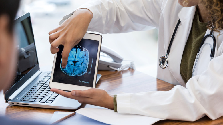 doctor pointing at scan of brain on tablet